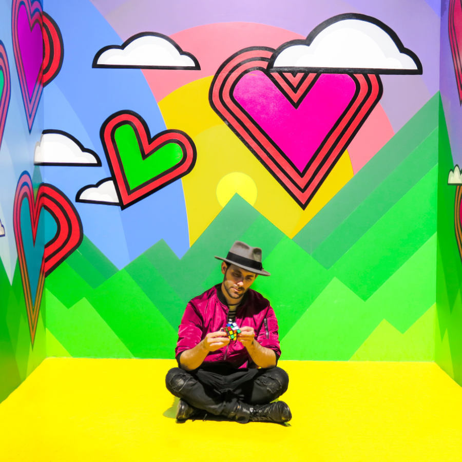 man sitting in a multicolored room with a rubix cube