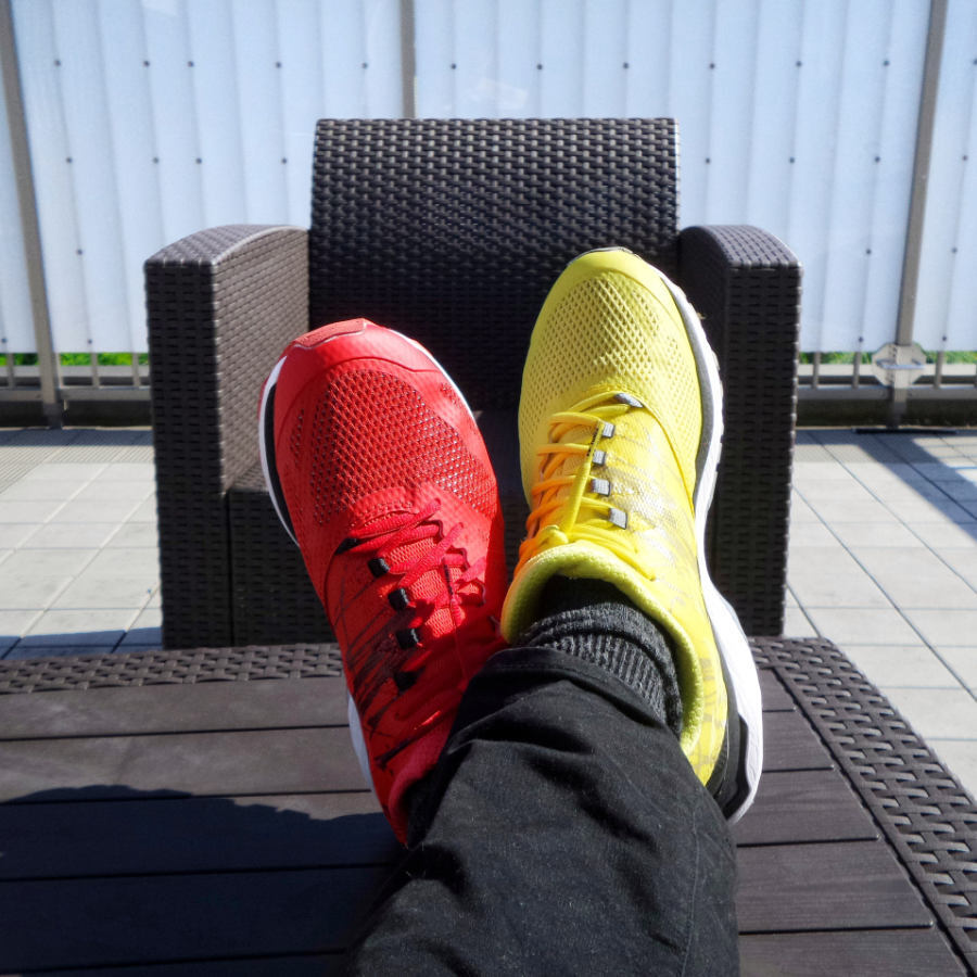 a pair of yellow and red sneakers on a person with legs on a table