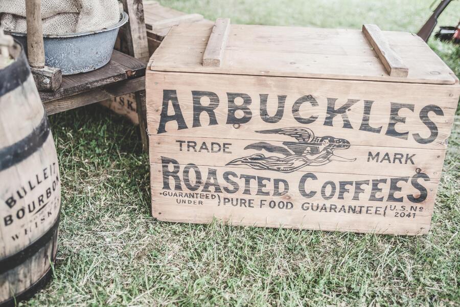 Wooden crate with Arbuckels Coffee Brand next to barrels